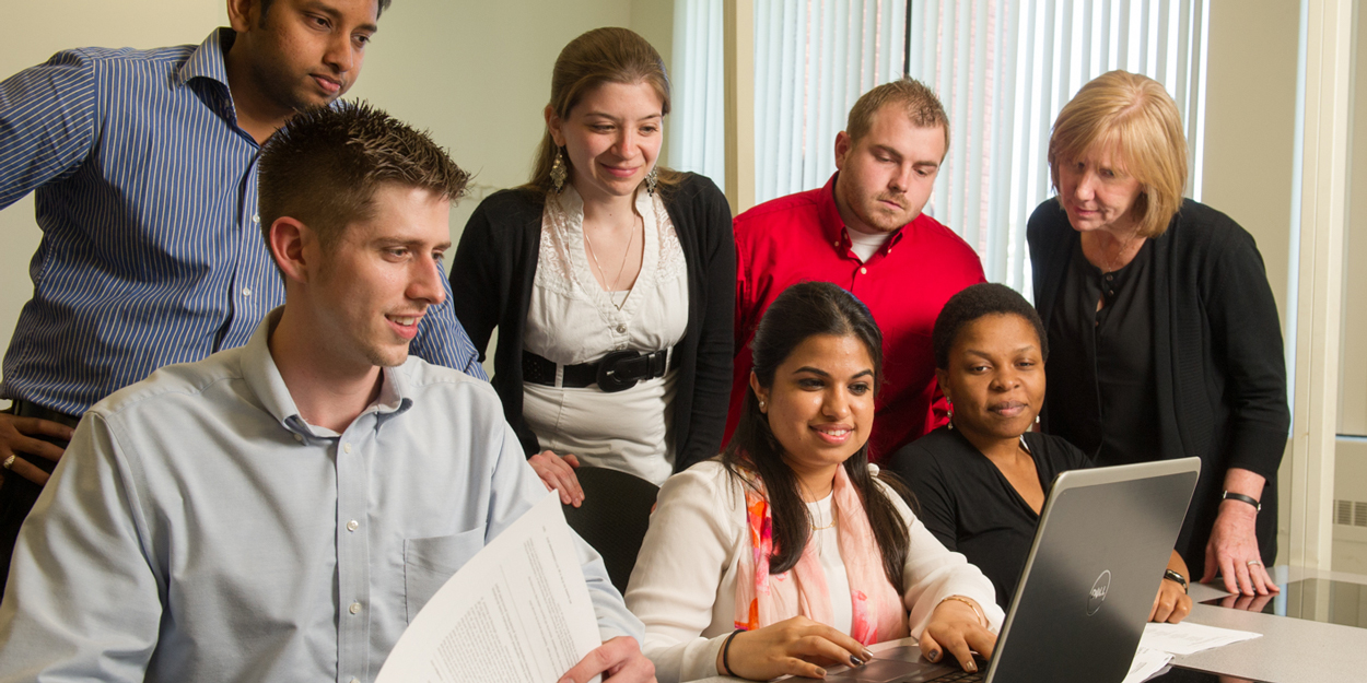 Several students around a computer at a desk.