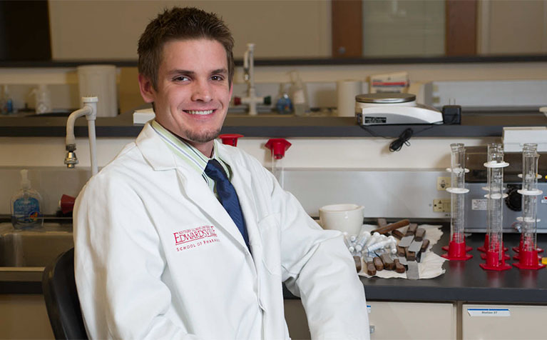 An alumni of the SIUE School of Pharmacy sitting in front of a lab table