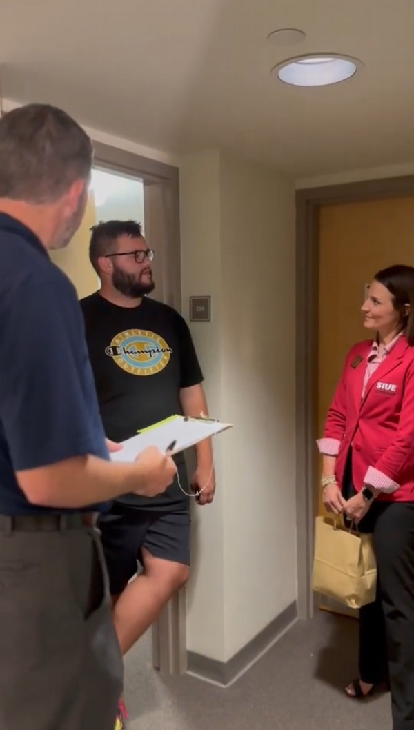 Three staffers stand in conversation in residence hallway