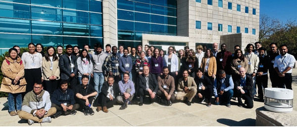 Dozens of conference attendees pose for photo in front of engineering building